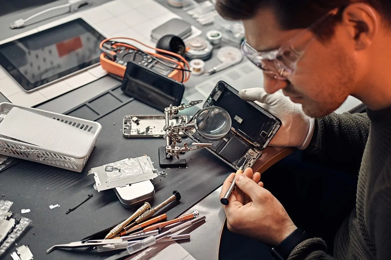 Technician repairing computer hardware at a service workstation.